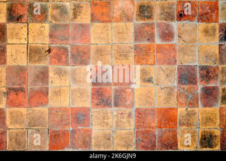 Orange brown purple old shabby worn out floor tiles with damages cracks dirt caverns potholes and paint stains. Art design background texture. Stock Photo