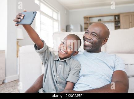 The memories we make with our family is everything. a father and son using a cellphone on the sofa at home. Stock Photo