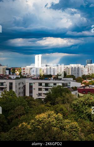 Balcony view of dramatic skies with storm clouds and light falling on skyscraper. Stock Photo