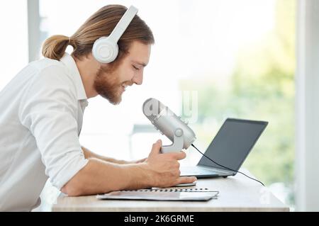 Inspiring his audience with riveting content. a young businessman using a microphone during a broadcast in an office. Stock Photo