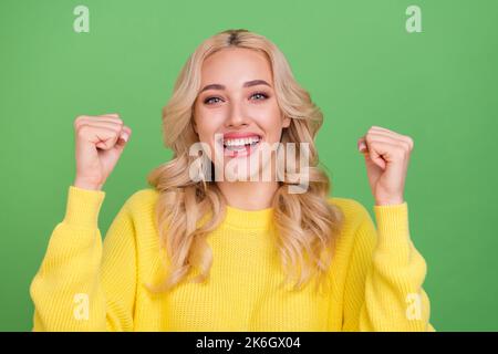 Photo of hooray young blond lady hands fists yell wear yellow pullover isolated on green color background Stock Photo