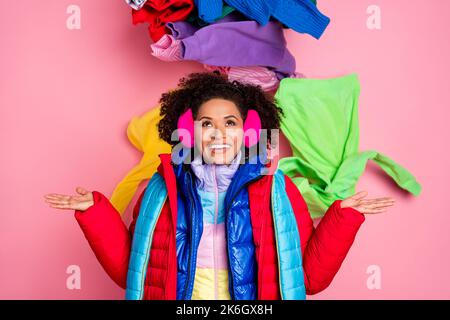 Portrait of attractive cheerful girl wearing warm outfit things falling down isolated over pink pastel color background Stock Photo