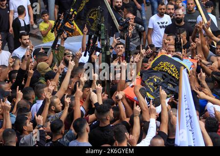 Jenin, Palestine. 14th Oct, 2022. (EDITORS NOTE: Image depicts death)Mourners and gunmen carry the body of 18-year-old Palestinian gunman Matin Dabbaya, who was killed during clashes with the Israeli army in the Jenin refugee camp near the city of Jenin in the occupied West Bank. The Israeli army stormed the Jenin refugee camp to arrest a wanted man. The Palestinian Ministry of Health said that a Palestinian was killed and 14 others, including a doctor, were wounded during this military operation. Credit: SOPA Images Limited/Alamy Live News Stock Photo