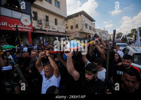 Jenin, Palestine. 14th Oct, 2022. (EDITORS NOTE: Image depicts death)Mourners and gunmen carry the body of 18-year-old Palestinian gunman Matin Dabbaya, who was killed during clashes with the Israeli army in the Jenin refugee camp near the city of Jenin in the occupied West Bank. The Israeli army stormed the Jenin refugee camp to arrest a wanted man. The Palestinian Ministry of Health said that a Palestinian was killed and 14 others, including a doctor, were wounded during this military operation. (Photo by Nasser Ishtayeh/SOPA Images/Sipa USA) Credit: Sipa USA/Alamy Live News Stock Photo