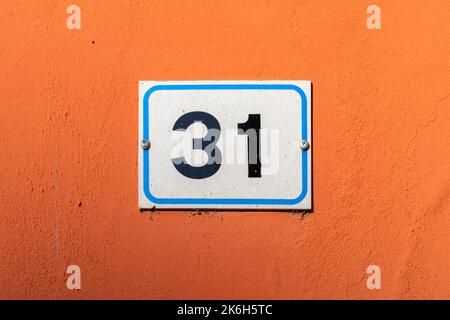 Number thirty one on enamel plate on painted orange wall Stock Photo