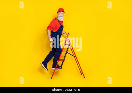 Full body photo of pensioner technician climb up tool ladder isolated on vibrant color background Stock Photo