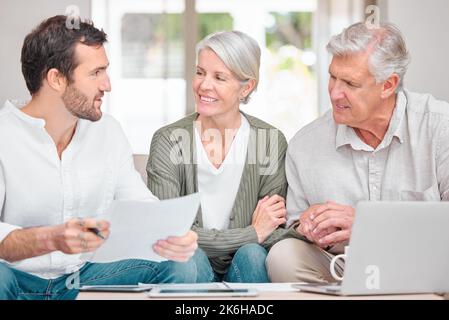 Helping them through retirement. a handsome young male financial advisor helping a senior couple with their finances in their home. Stock Photo