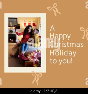 Composition of christmas greetings and biracial couple taking selfie on yellow background Stock Photo
