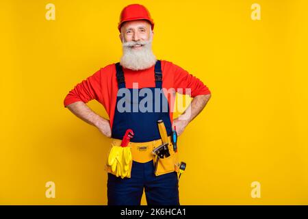 Photo portrait of attractive grandparent constructor confident experienced wear blue workwear overall helmet isolated on yellow background Stock Photo
