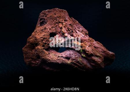 Red rough real lava stone macro focused and isolated on black surface isolated Stock Photo