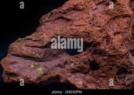 Red rough real lava stone macro focused and isolated on black surface isolated Stock Photo