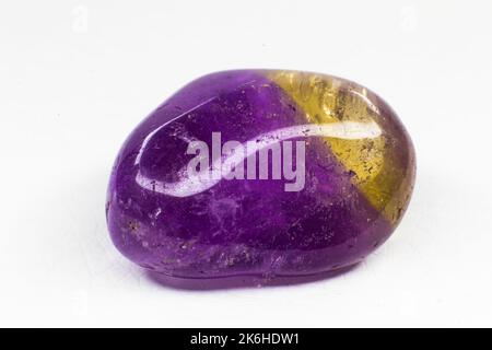 Real tumbled Ametrine stone macro isolated on white surface. Purple crystal with a bit of yellow coloration on the end. Stock Photo