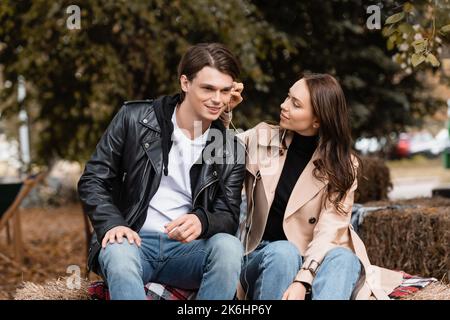 smiling young woman adjusting wired earphone in ear of happy boyfriend,stock image Stock Photo