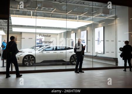 Shoppers look at a Polestar hatchback EV car in the showroom of Polestar Battersea, in the re-opened Battersea Power Station retail space, on 14th October 2022, in London, England. Polestar is a Swedish automotive brand established in 1996 by Volvo Cars' partner Flash/Polestar Racing and acquired in 2015 by Volvo, which itself was acquired by Geely in 2010. It is headquartered in Torslanda outside Gothenburg, Sweden. The re-opening of Battersea Power Station coincided with Prime Minister Liz Truss sacking of her Chancellor, Kwasi Kwarteng amid continued economic instability, the result of the Stock Photo