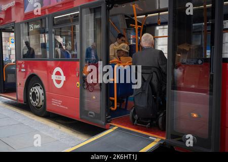 A disabled man on a mobility scooter, boards a London bus using the special ramp for disability passengers, on 12th October 2022, in London, England. Stock Photo