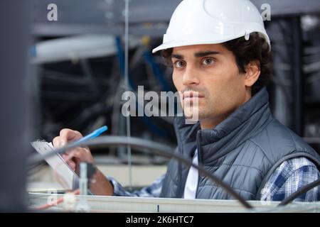 handsome young male builder writing on clipboard Stock Photo