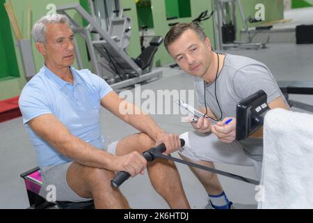senior man working out in gym with personal trainer Stock Photo