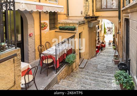 Bellagio, Lombardy, Italy - September 5, 2022: Outdoor cozy street restaurant in the small picturesque village Bellagio on Lake Como. Stock Photo