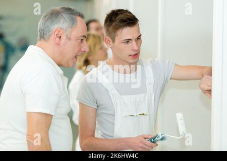 two workers paint a wall in the room using rollers Stock Photo