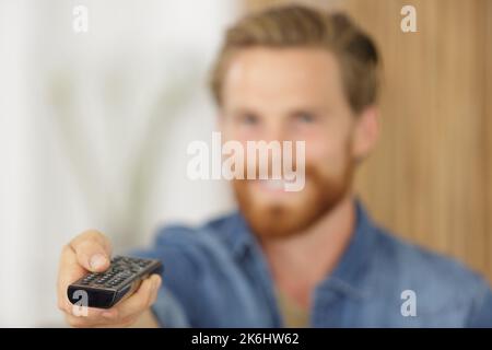 remote control held by blurred young man in the background Stock Photo