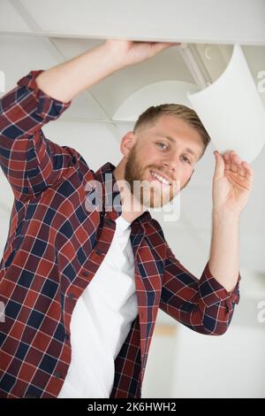 happy man fixes the lamp in his house Stock Photo