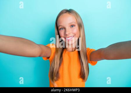 Selfie closeup photo of young blonde hair positive smiling blogger hold camera wear stylish bright orange t-shirt isolated on aquamarine color Stock Photo