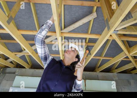 female worker hammering beams of the ceiling Stock Photo