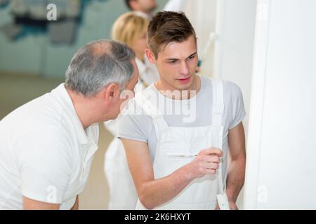 portrait of a painter watching apprentice working Stock Photo