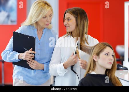 hairdressing apprentice ironing the clients hair Stock Photo