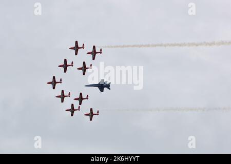 RCAF Snowbirds flying in formation, along with a fighter jet. Two streams of smoke on either side of the formation. Stock Photo