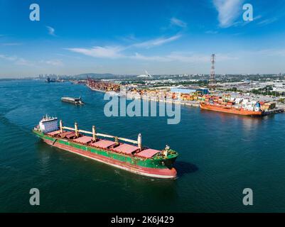 Aerial view of a fully loaded cargo ship leaving the Montreal Port and going downriver on the St.Lawrence River. Stock Photo