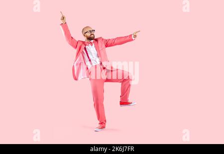 Funny dancer in pink suit, trainers and glasses dancing and having fun in studio Stock Photo