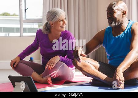 Happy senior diverse couple practicing yoga and talking Stock Photo