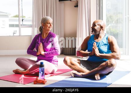 Happy senior diverse couple practicing yoga and talking Stock Photo