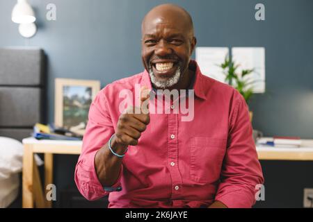 Happy african american senior man making video call smiling and giving thumb up sign to camera Stock Photo