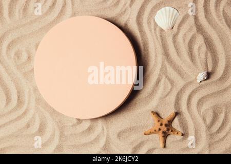 Empty beige round platform podium for cosmetics or products presentation, sea shell and starfish on natural beige beach sand background. Wavy curved Stock Photo