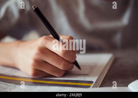 Kid affected by dyslexia doing homework, writing, reading notebook task using colorful overlay strip. Education, learning disability, reading Stock Photo