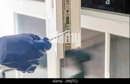 master with a screwdriver sets fittings on the window Stock Photo