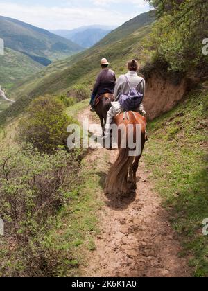 Horse trekking pony ride for western and European holiday maker, tourists and visitors given by Tibetan horseman / man / ethnic people of Tibet, resident or local to the walled ancient Chinese town of Songpan in northern Sichuan province, China. (126) Stock Photo