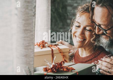 Love and christmas gifts concept leisure activity with young mature man and woman exchanging presents in winter holiday at home with smile and happine Stock Photo