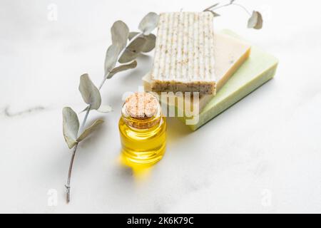 Natural handmade organic soap bars stack on white background with euacalyptus leaves and essential oil. Natural organic cosmetics. Stock Photo