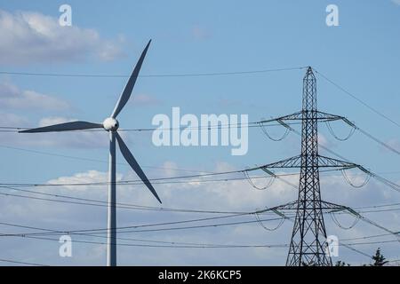Wind turbine and electricity pylon on blue sky background Stock Photo