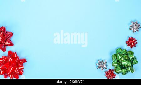 Beautiful Christmas red green silver present ribbon bow over light blue background with space for text. New Year gift. Many colorful bows on blue. Top Stock Photo