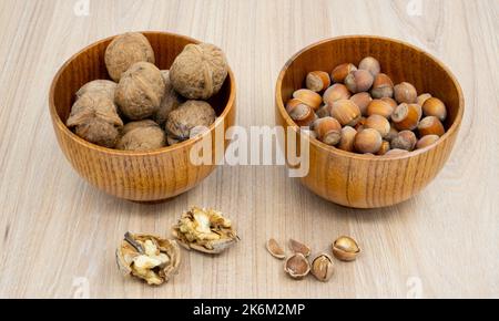 Hazelnuts and walnuts in a bowl with a few cracked next to it on the table. Stock Photo