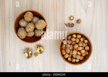 Hazelnuts and walnuts in a bowl with a few cracked next to it on the table. Flat lay. Stock Photo