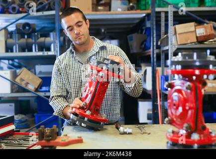 Man assembling plumbing fixture in workshop Stock Photo