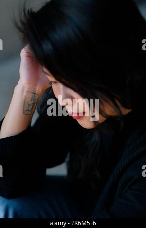 Close-up of minimalist line art tattoo inspired by the book and film, Call Me By Your Name. Artwork is on an Asian woman's wrist, face in profile. Stock Photo