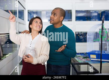 Positive couple choosing aquarium fish in shop Stock Photo