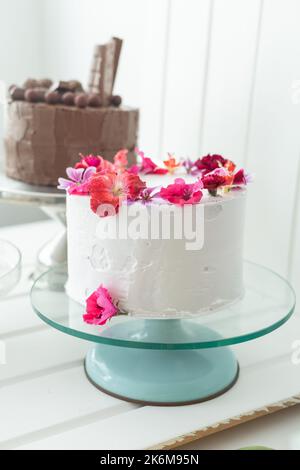 two delicious cakes, one decorated with cream and edible rose petals, the other with chocolate, sweet food for celebrations in studio Stock Photo