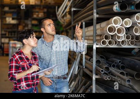Man and woman working in warehouse, checking documents and poitning finger Stock Photo